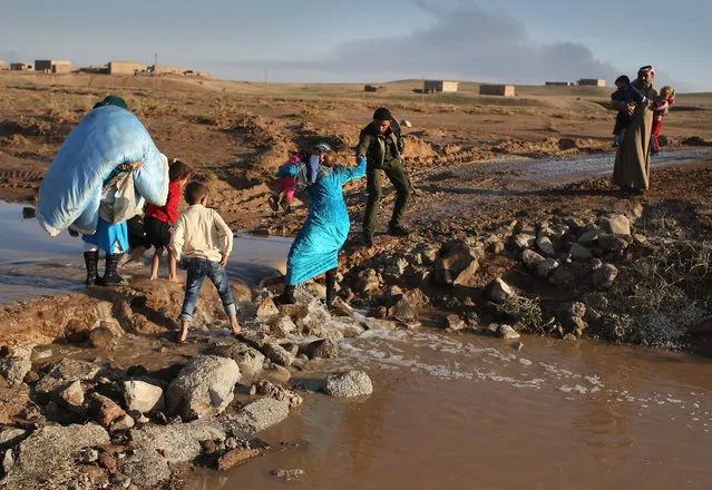 A Rojava soldier helps villagers return home after troops from the Syrian Democratic Forces, a coalition of Kurdish and Arab forces, retook a town on November 11, 2015 near Hasaka, in the autonomous region of Rojava, Syria. The armed forces of the predominantly Kurdish region in northern Syria have been retaking territory from ISIL extremists with the help of airstrikes from the U.S. led coalition. (Photo by John Moore/Getty Images)