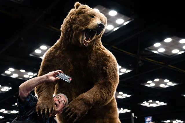 An attendee takes a selfie with a taxidermy bear during the National Rifle Association (NRA) annual convention at the Indiana Convention Center in Indianapolis, Indiana on Friday, April 14, 2023. (Photo by Demetrius Freeman/The Washington Post)