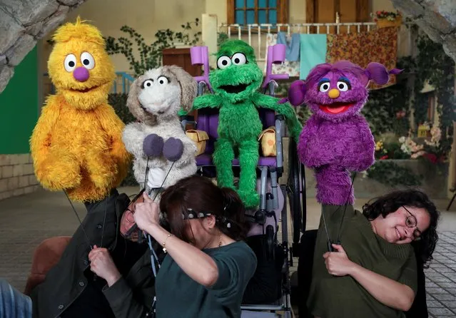 Puppeteers manipulate puppets including “Ameera”, the new muppet character who uses a purple wheelchair or crutches to get around due to a spinal cord injury, during the filming of a scene on the set of the children's TV show “Ahlan Simsim”, in a studio in Amman, Jordan, March 28, 2022. (Photo by Alaa Al Sukhni/Reuters)