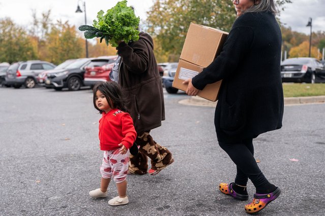 The son of a federal employee walks alongside her after collecting food from a Capital Area Food Bank distribution center in Hyattsville, Maryland on October 28, 2025. (Photo by Nathan Howard/Reuters)