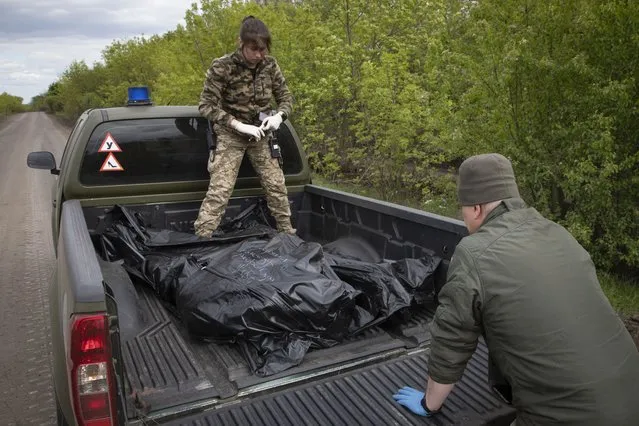 Military medics load bodies of the killed Ukrainian soldiers in plastic bags on a car on the road near Bakhmut, Donetsk region, Ukraine, Thursday, May 11, 2023. (Photo by Boghdan Kutiepov/AP Photo)