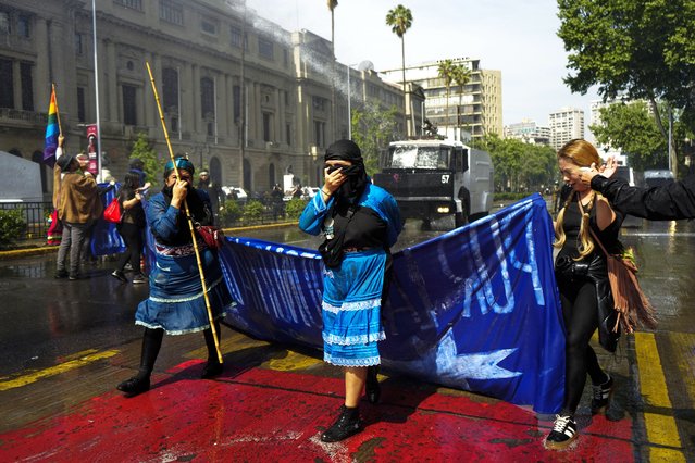 Police fire water and tear gas at Mapuche Indigenous women and supporters during a march to demand autonomous territory for Chile's Indigenous people and the release of pro-Mapuche detainees, in Santiago, Chile, October 13, 2024. (Photo by Esteban Felix/AP Photo)