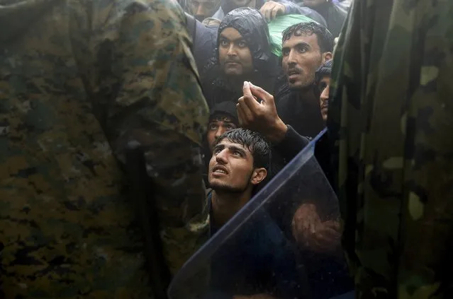 Migrants and refugees beg Macedonian soldiers to allow them passage to cross the border from Greece into Macedonia during a rainstorm, near the Greek village of Idomeni, September 10, 2015. (Photo by Yannis Behrakis/Reuters)