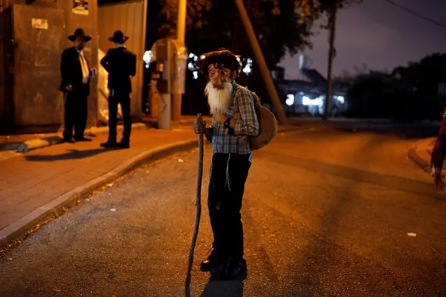 A youth wearing a dress-up costume marking the Jewish holiday of Purim, a celebration of the Jews' salvation from genocide in ancient Persia, amid the coronavirus disease (COVID-19) crisis, stands in a street in Bnei Brak, near Tel Aviv, Israel on February 25, 2021. (Photo by Nir Elias/Reuters)