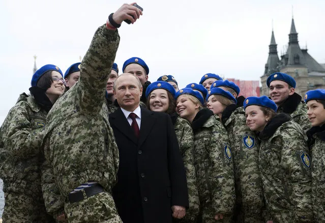 Russian President Vladimir Putin (C) poses for a selfie with young activists at the Red Square in Moscow on November 4, 2015 during celebrations for National Unity Day marking the 403rd anniversary of the 1612 expulsion of Polish occupation forces from the Kremlin. (Photo by Natalia Kolesnikova/AFP Photo)