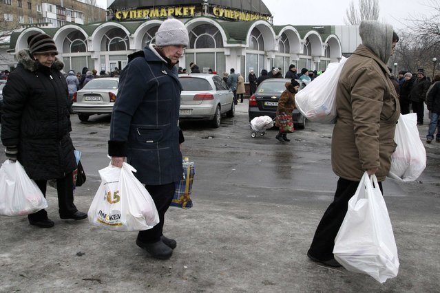 Local residents carry bags after receiving it as humanitarian aid at a grocery store in Donetsk, January 29, 2015. (Photo by Alexander Ermochenko/Reuters)