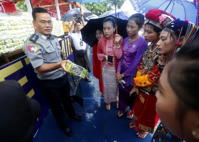 A police officer informs people dressed in ethnic traditional attire about illegal drugs during a “Destruction Ceremony of Seized Narcotic Drugs” held to mark the International Day Against Drug Abuse and Illicit Trafficking, in Yangon, Myanmar, 26 June 2023. Myanmar authorities destroyed an assortment of drugs worth over 446 million dollars all over the country. (Photo by Nyein Chan Naing/EPA)