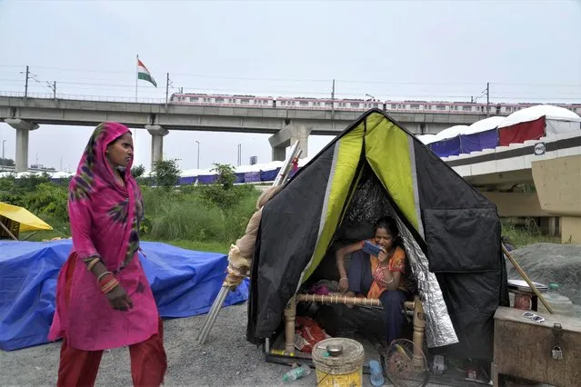 People evacuated from the flood plains of the river Yamuna rest in makeshift tents along a street in New Delhi, India, Thursday, July 13, 2023. Residential areas close to the river were flooded, submerging roads, cars and homes, leading to the evacuation of thousands of people from low-lying areas in the country's capital city. More than 100 people were killed this week after record monsoon rains led to massive waterlogging, road caves-in, collapsed homes and gridlocked traffic, officials said Thursday. (Photo by Manish Swarup/AP Photo)