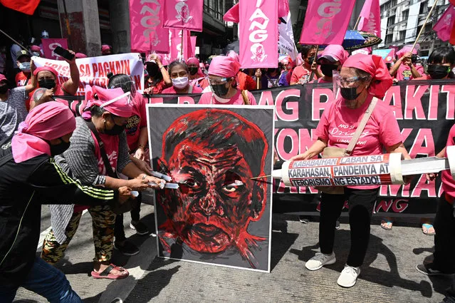Members of a women's rights group deface an image of Philippine President Rodrigo Duterte during a protest near the presidential palace on International Women's Day in Manila on March 8, 2021. (Photo by Ted Aljibe/AFP Photo)