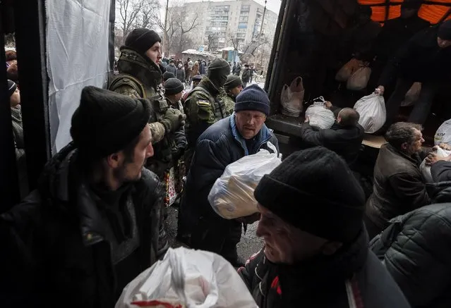 Local residents unload a truck of humanitarian aid near Ukrainian servicemen in Debaltseve, eastern Ukraine, February 6, 2015. (Photo by Gleb Garanich/Reuters)