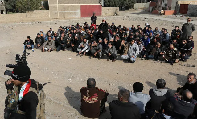Men sit on the ground as an Iraqi Special forces intelligence team check their ID cards as they search for Islamic State fighters in Mosul, Iraq November 27, 2016. (Photo by Goran Tomasevic/Reuters)