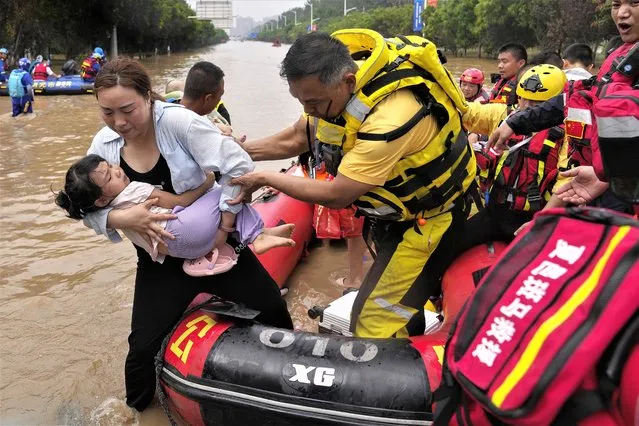 A rescuer helps a woman with a child disembark from a rubber boat as trapped residents evacuate through floodwaters in Zhuozhou in northern China's Hebei province, south of Beijing, Wednesday, August 2, 2023. (Photo by Andy Wong/AP Photo)
