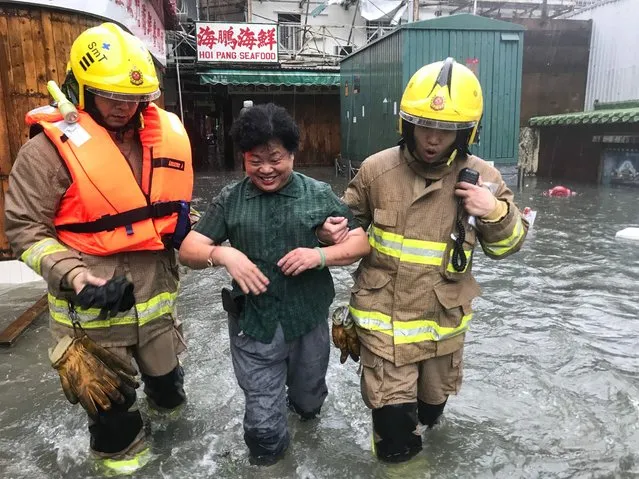 A woman reacts as fire rescue workers assist her through floodwaters in the village of Lei Yu Mun during Super Typhoon Mangkhut in Hong Kong on September 16, 2018. (Photo by Anthony Wallace/AFP Photo)