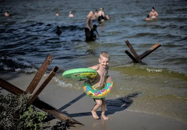 A boy plays near an anti-tank construction at the bank of Dnipro river as temperature reached 40 degrees Celsius (104 degrees Fahrenheit), amid Russia's attack on Ukraine, in Zaporizhzhia, Ukraine on August 6, 2023. (Photo by Viacheslav Ratynskyi/Reuters)