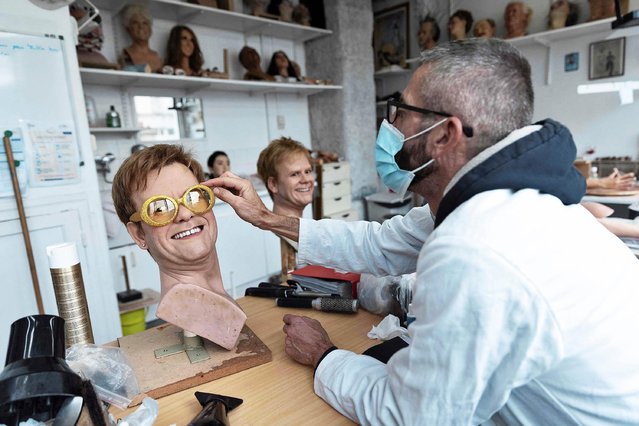 An employee adjusts the hair of Sir Elton John wax statue's wig at the Musee Grevin wax museum in Paris on May 12, 2021, ahead of its reopening following the closure as part of restrictions to fight the spread of the Covid-19 pandemic. (Photo by Thomas Samson/AFP Photo)