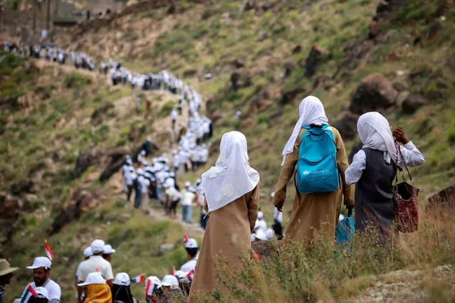 Yemeni volunteers form a human chain to pass food aid, supplied by the UAE Red Crescent, to mountainous towns on the outskirts of the country' s third- city of Taiz on October 16, 2018. (Photo by Ahmad Al-Basha/AFP Photo)