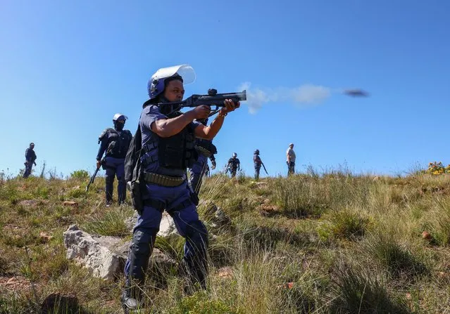 A policeman fires teargas at protesters from Railton informal settlement who are protesting over the high electricity tariffs and the municipality's indigent grant, in Swellendam, 200km outside Cape Town, South Africa on September 20, 2023. (Photo by Esa Alexander/Reuters)