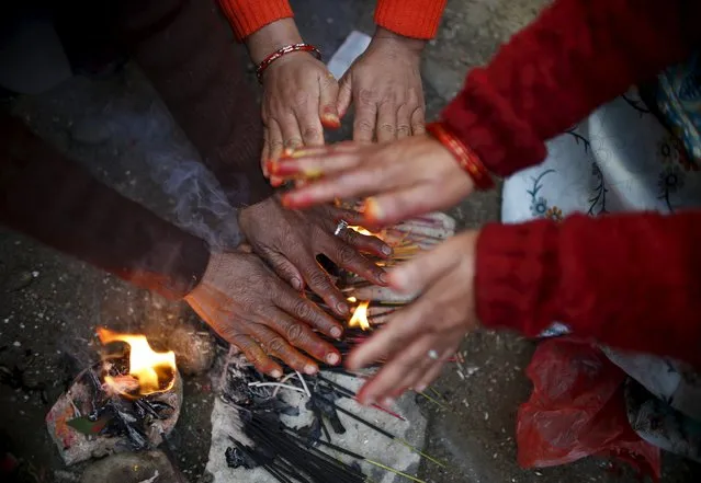 Hands of devotees try to keep them warm near burning incense during the Swasthani Brata Katha festival at Sankhu in Kathmandu, Nepal, January 24, 2016. (Photo by Navesh Chitrakar/Reuters)