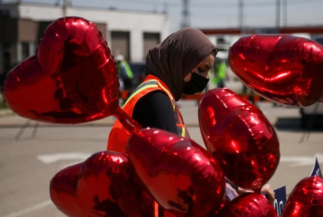 A volunteer places a sign outside the Islamic Centre of Southwest Ontario, next to heart-shaped balloons, before a funeral of the Afzaal family that was killed in what police describe as a hate-motivated attack, in London, Ontario, Canada on June 12, 2021. (Photo by Carlos Osorio/Reuters)