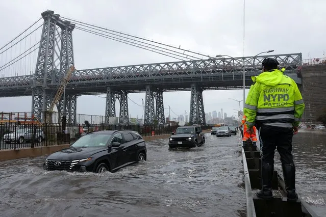 A police officer from the NYPD Highway Patrol looks to motorists drive through a flooded street after heavy rains as the remnants of Tropical Storm Ophelia bring flooding across the mid-Atlantic and Northeast, at the FDR Drive in Manhattan near the Williamsburg Bridge, in New York City, U.S., September 29, 2023. (Photo by Andrew Kelly/Reuters)