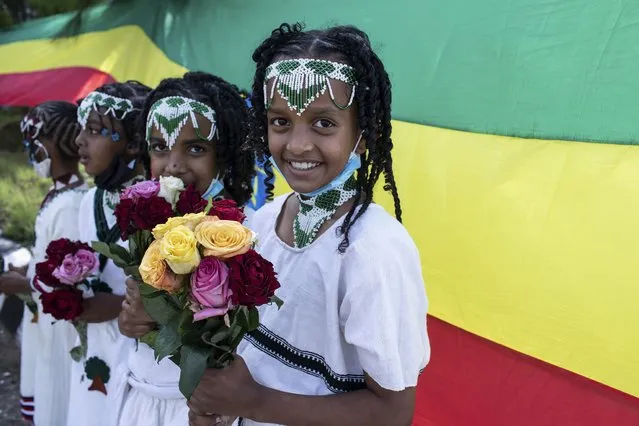 Children hold flowers to greet the arrival of Ethiopia's Prime Minister Abiy Ahmed, ahead of a final campaign rally, in the town of Jimma in the southwestern Oromia Region of Ethiopia Wednesday, June 16, 2021. The country is due to vote in a general election on Monday, June, 21, 2021. (Photo by Mulugeta Ayene/AP Photo)