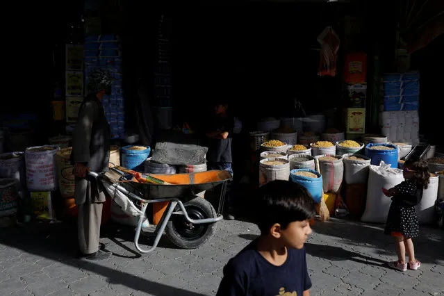 Baba Karim with his wheelbarrow stands next to a shop in Kabul, Afghanistan on September 3, 2023. (Photo by Ali Khara/Reuters)