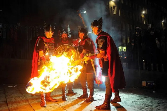 Members of the Up Helly AA Vikings from Shetland light their torches as they prepare to take part in a torchlit procession through the streets of Edinburgh in Scotland, December 30, 2016, as the city begins to celebrate Hogmanay. The procession is the opening event of Edinburghs Hogmanay 2016/17. Over 40,000 people are expected to throng the streets of the capital to watch the torch carriers as they illuminate the city, culminating in a breath-taking fireworks finale. (Photo by Andy Buchanan/AFP Photo)