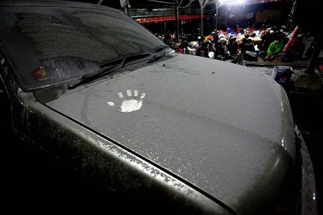 A hand print is seen on the hood of a car covered with volcanic ash from the eruption of Mount Sinabung, in Tiga Nderket village on November 4, 2013. (Photo by Binsar Bakkara/Associated Press)
