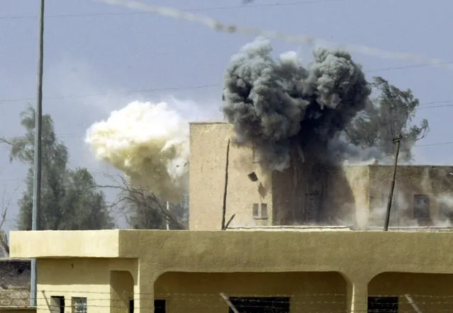 A building receives tank fire from U.S. Marine Expeditionary Unit tanks beside the port of Umm-Qasr in southern Iraq as pockets of Republican Guard resistance remain in a residential area beside the port, March 2003. (Photo by Desmond Boylan/Reuters)