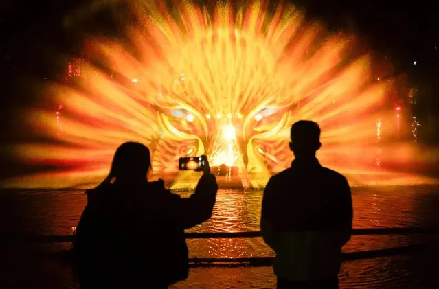 Visitors watch a projection onto a water fountain during a sound a light installation, part of the the Enchanted Forest and Winter Illuminations at Stockeld Park in Wetherby, West Yorkshire on Wednesday, November 22, 2023. (Photo by Danny Lawson/PA Images via Getty Images)