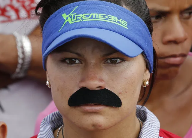 A woman dons a fake mustache emulating that of Venezuela's Nicolas Maduro, at a pro-government rally in Caracas, Venezuela, Saturday, February 2, 2019. Maduro called the rally to celebrate the 20th anniversary of the late President Hugo Chavez's rise to power. (Photo by Ariana Cubillos/AP Photo)