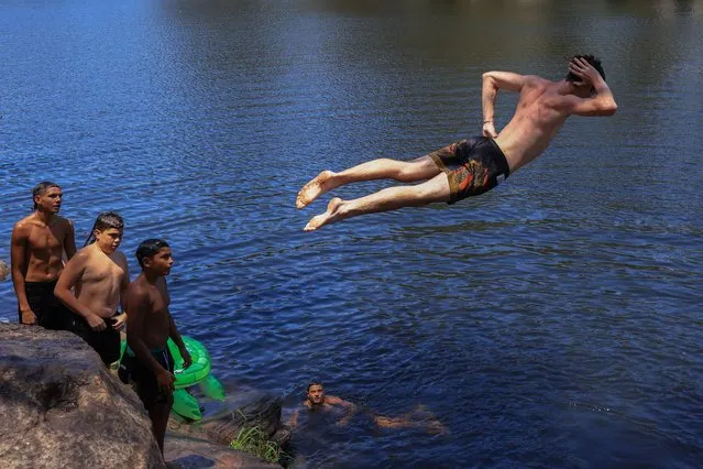 A boy jumps from the rocks into the water at Lake Parramatta, a heritage-listed man-made reservoir on December 08, 2023 in Sydney, Australia. A severe heat wave was predicted for the weekend, a precursor of hot and dry conditions expected for the rest of the summer which will also bring heightened bushfire risk. (Photo by Jenny Evans/Getty Images)