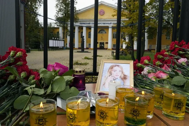 Flowers, candles and a portrait of one of victims are displayed on a table outside the Perm State University in Perm, about 1,100 kilometers (700 miles) east of Moscow, Russia, Tuesday, September 21, 2021. (Photo by Dmitri Lovetsky/AP Photo)