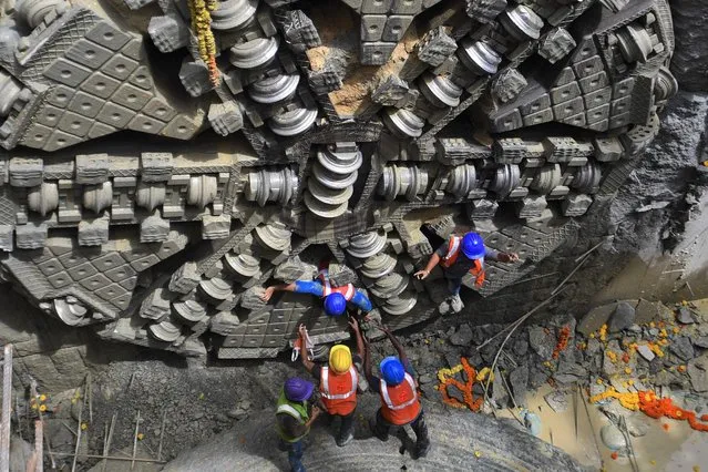 Construction workers celebrate after the Tunnel Boring Machine (TBM) “Urja” emerged at the upcoming Shivaji Nagar underground metro station after drilling a distance of 855 metres for over a year, in Bangalore on September 22, 2021. (Photo by Manjunath Kiran/AFP Photo)