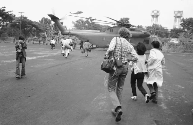 Americans and Vietnamese run for a U.S. Marine helicopter in Saigon during the evacuation of the city, April 29, 1975. (Photo by AP Photo)