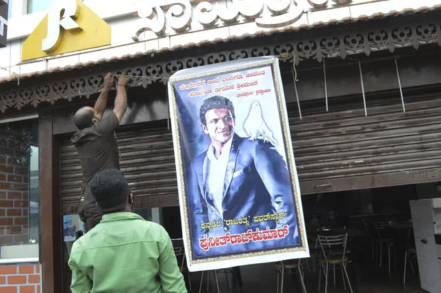 A poster of actor Puneeth Rajkumar is hung outside a hotel with closed shutters after news of the actor's death, in Bengaluru, India, Friday, October 29, 2021. Rajkumar, a top star of southern Indian regional films, died on Friday after a massive heart attack, a hospital statement said. He was 46. Rajkumar was rushed to Vikram hospital in Bengaluru, the capital of southern Karnataka state, after he complained of chest and died there, the statement said. The Press Trust of India news agency said he had a two-hour workout in a gymnasium and was rushed to the hospital straight from there. (Photo by AP Photo/Stringer)