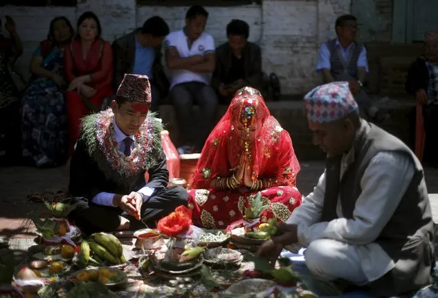 Groom Khil Bahadur Ghale (L), 25, and bride Bishma Punj (C), 24, perform rituals during their wedding ceremony at a temple in Kathmandu, Nepal May 4, 2015. The couple decided to go ahead with the wedding despite the recent earthquake that struck the country last week. (Photo by Adnan Abidi/Reuters)