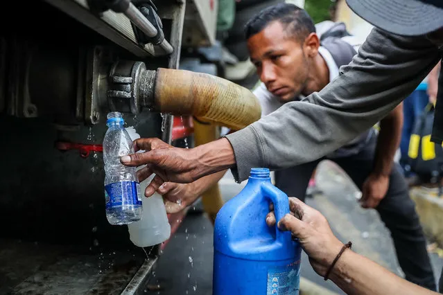 A group of people is supplied with water from a tanker in Caracas, Venezuela, 31 March 2019. The lack of water caused by a week of blackouts in Venezuela ended up pushing Venezuelans into the streets to protest against the government of Nicolas Maduro in a day in which there were clashes in Caracas with gunfire and it is not yet known if anyone was injured. (Photo by Miguel Gutierrez/EPA/EFE)