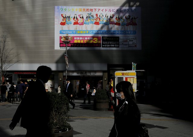 People walk past an advertisement for Japanese idol group Kamen Joshi (Masked Girls) in Tokyo's Akihabara district, Japan March 17, 2016. (Photo by Toru Hanai/Reuters)