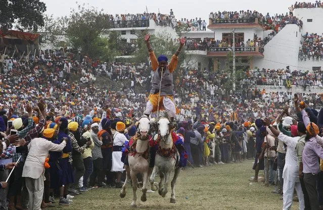 A “Nihang”, or a Sikh warrior, rides two horses as he performs during the Holla Mohalla festival in Anandpur Sahib in the northern state of Punjab, India, March 24, 2016. “Hola Mohalla”, or the festival of Nihangs, is celebrated during the festival of Holi, marking the congregation of Sikh devotees from all over the country. (Photo by Ajay Verma/Reuters)