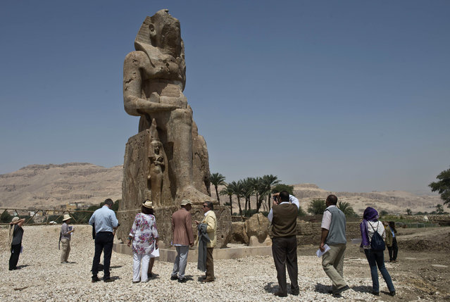Tourists and journalists stand next to a newly displayed statue of pharaoh Amenhotep III and his wife Tiye (Down) in Egypt's temple city of Luxor on March 23, 2014. Two colossal statues of pharaoh Amenhotep III were unveiled by archaeologists today in their original sites in the funerary temple of the king, on the west bank of the Nile in Luxor, adding to the existing two famous ancient Memnon colossi. (Photo by Khaled Desouki/AFP Photo)