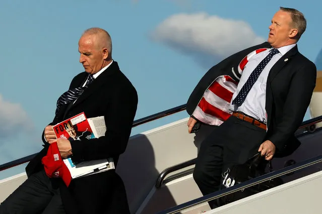 White House Director of Oval Office Operations Keith Schiller (L) carries a red USA hat and a copy of Fortune magazine with U.S. President Donald Trump on the cover as he and Communications Director Sean Spicer (R) deplane from Air Force One at Joint Base Andrews, Maryland, U.S. March 2, 2017. (Photo by Jonathan Ernst/Reuters)