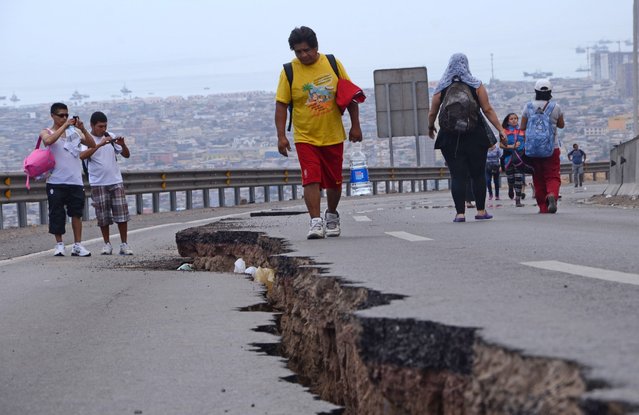 People walk along a cracked road in Iquique, northern Chile, on April 2, 2014 a day after a powerful 8.2-magnitude earthquake hit off Chile's Pacific coast. (Photo by Aldo Solimano/AFP Photo)