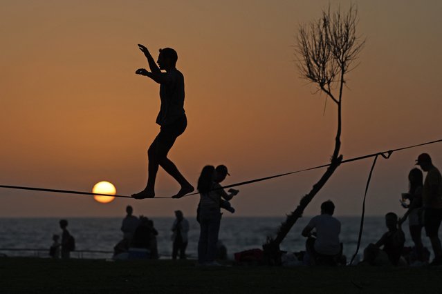 A man is silhouetted against the setting sun as he balances on a wire at a beach in the Israeli coastal city of Tel Aviv on April 19, 2024. Fears of a major regional spillover from the Gaza war have soared since Iran carried out its first-ever attack directly targeting Israel on April 13-14. (Photo by Ahmad Gharabli/AFP Photo)