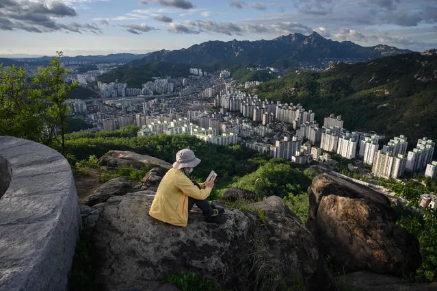 A photo taken on June 7, 2019 shows a woman looking at a phone before apartment buildings of the Seoul city skyline. (Photo by Ed Jones/AFP Photo)