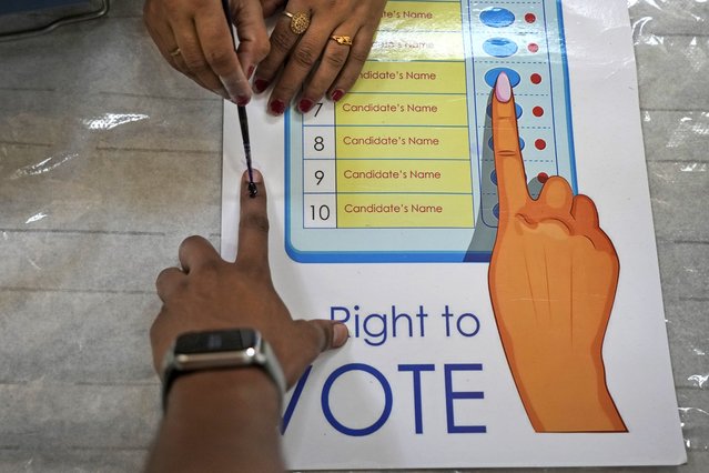 A polling officer applies indelible ink mark on the index finger of a voter during the sixth round of polling in India's national election in New Delhi, India, Saturday, May 25, 2024. (Photo by Manish Swarup/AP Photo)