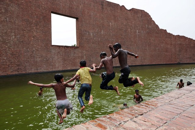 Children jump into the water body of Martyred Intellectuals Memorial at Rayerbazar, to cool themselves during a heatwave in Dhaka, Bangladesh, on April 23, 2024. (Photo by Mohammad Ponir Hossain/Reuters)