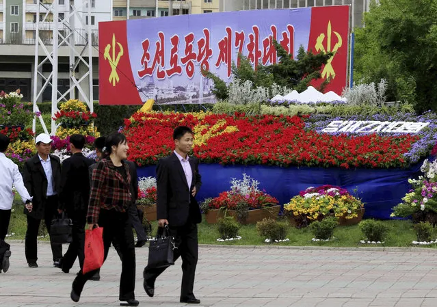 Pedestrians walk by a flower arrangement and billboard with the words “The 7th Congress of the Workers' Party of Korea” Thursday, May 5, 2016, in Pyongyang, North Korea. (Photo by Kim Kwang Hyon/AP Photo)