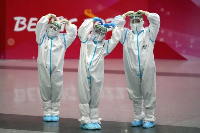Olympic workers in protective clothing pose for a picture at the Beijing Capital International Airport after the 2022 Winter Olympics, Monday, February 21, 2022, in Beijing, China. (Photo by Frank Augstein/AP Photo)