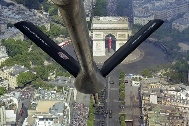 A picture taken on July 14, 2015 from a French Air Force C-135 FR refueling tanker aircraft over the Arc de Triomphe monument shows troops marching on the Champs-Elysees avenue during the annual Bastille Day military parade in Paris on July 14, 2015. (Photo by Franck Pennant/AFP Photo)